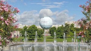 A fountain with multiple water jets in a park setting, surrounded by trees and buildings. - Location 31 Juillet au 15 Aout (Paris)
