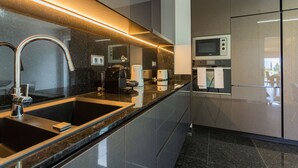 Eine moderne Küche mit Spüle aus Edelstahl, integriertem Mikrowellenherd und einer eleganten Arbeitsplatte.