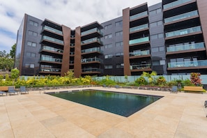 A modern building with multiple balconies, a swimming pool, and outdoor seating. - FLH Funchal Balcony Flat with Pool (Funchal)
