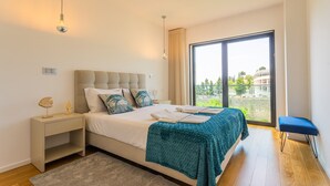 Ein Schlafzimmer mit Bett, Nachttisch und Blick durch ein großes Fenster.