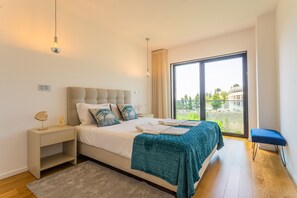 A bedroom with a bed, bedside table, and a view through a large window.