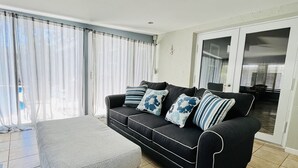 A modern living room with a grey sofa, striped cushions, and a grey ottoman.