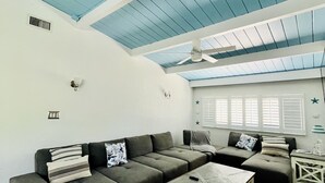 A modern living room with a sectional sofa, a coffee table, and a ceiling fan.
