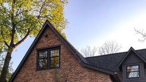 Une maison en briques avec un patio en pierre, une table de pique-nique et un parasol.