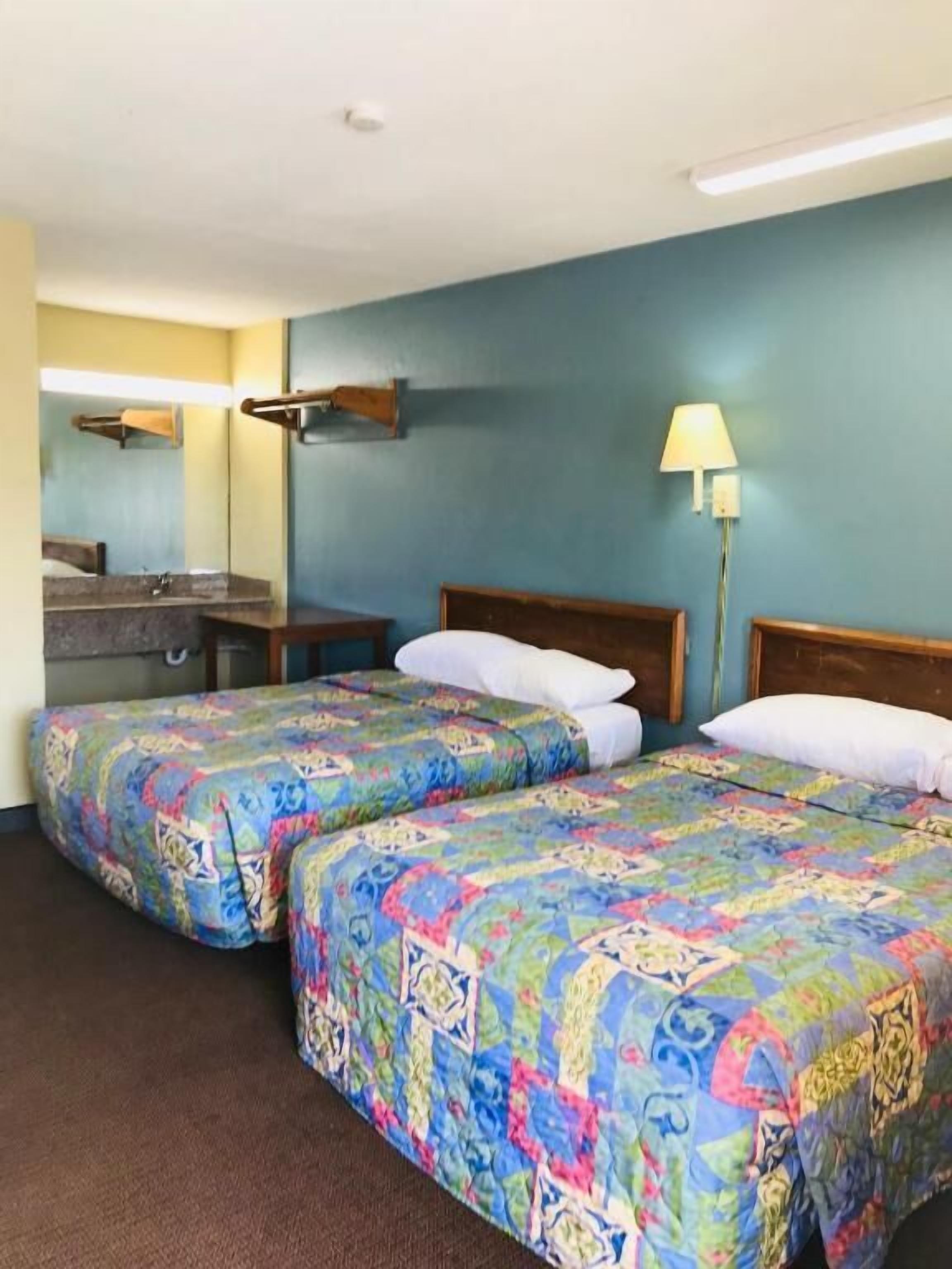 Una habitación de hotel con dos camas, un baño y una mesita de noche.