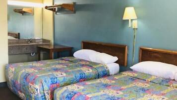 Una habitación de hotel con dos camas, un baño y una mesita de noche.