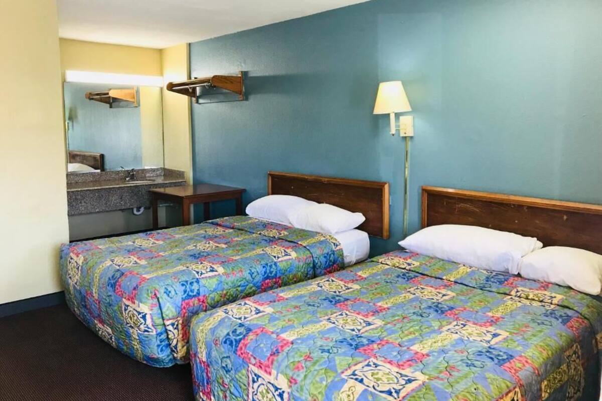 Ein Hotelzimmer mit zwei Betten, einem Badezimmer und einem Nachttisch.