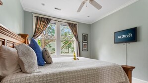 A bedroom with a bed, a television, and a window with curtains.
