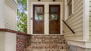 A set of wooden double doors with a brick staircase leading up to them.