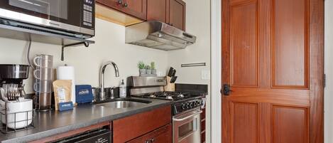 Una cocina con armarios de madera, estufa de acero inoxidable, microondas y lavavajillas.