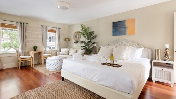 Un dormitorio amplio con una cama grande, una mesita, una silla y una planta en maceta.