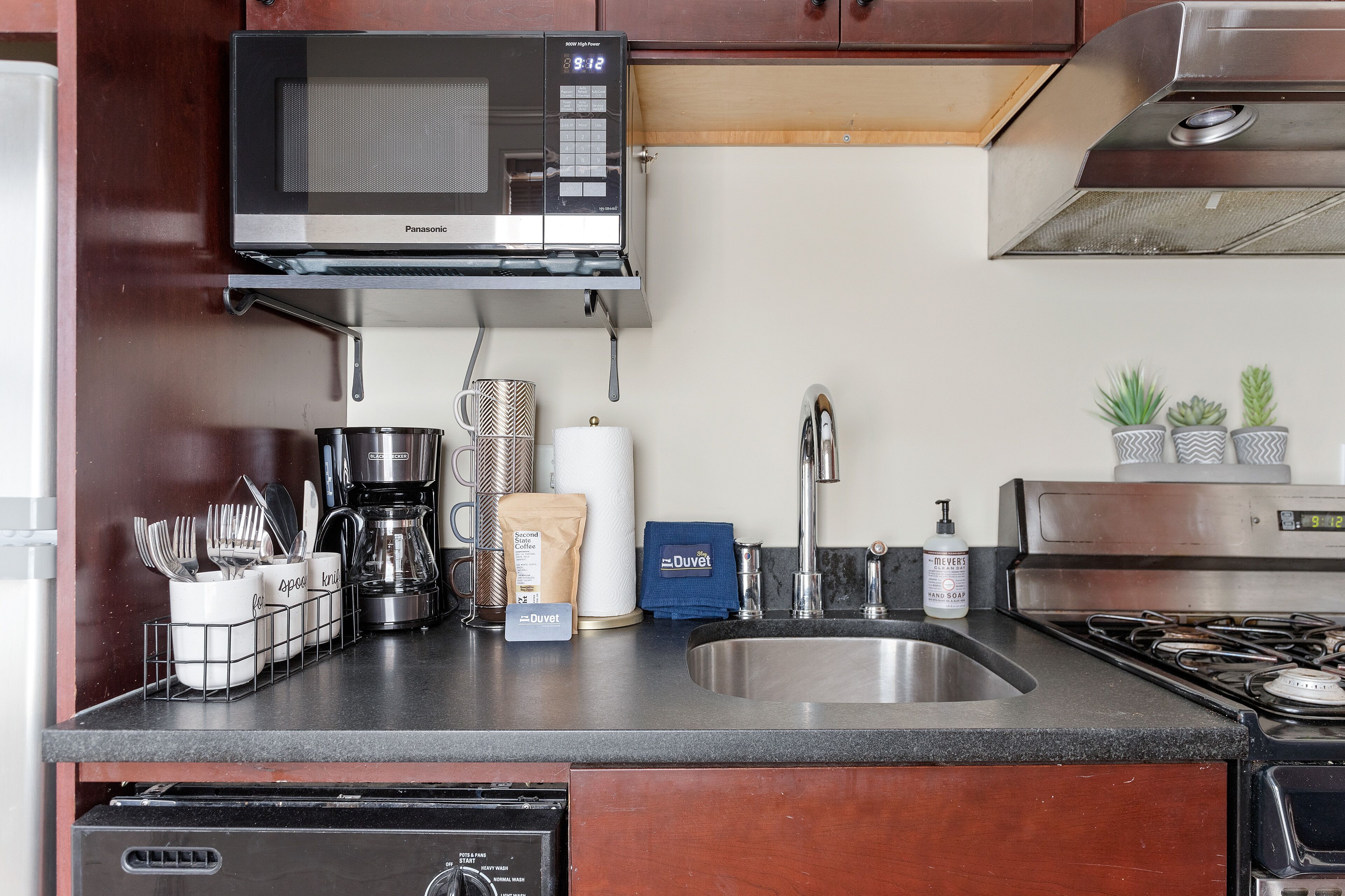 Una cocina equipada con microondas, cafetera, pileta y distintos utensilios de cocina.