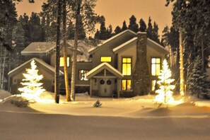 A snow-covered house with multiple windows and a chimney. - Windwood Breckenridge Luxury Mountain Home (Breckenridge)