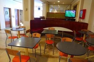 Un comedor con mesas, sillas, televisión y una barra.