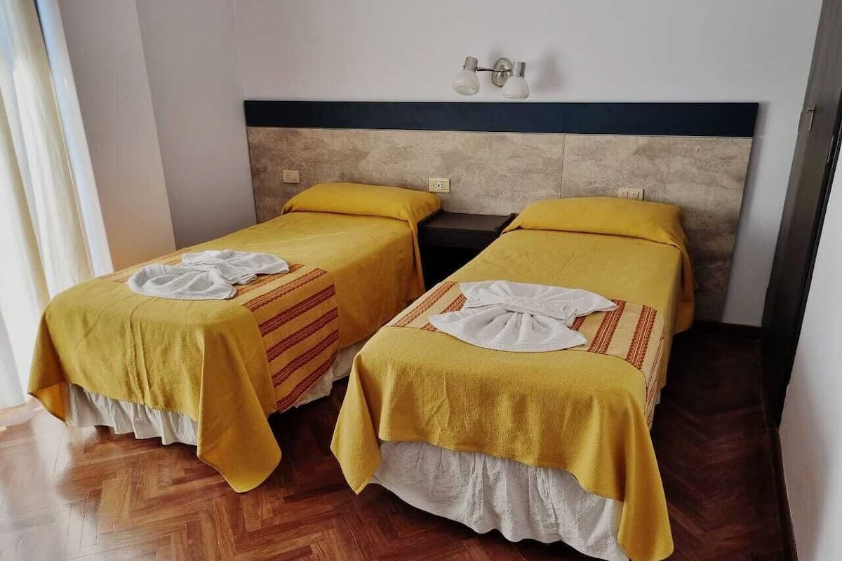 A room with two beds, each with a yellow bedspread and white pillows.