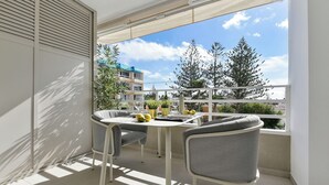 Un balcon avec une table, des chaises et des plantes en pot.
