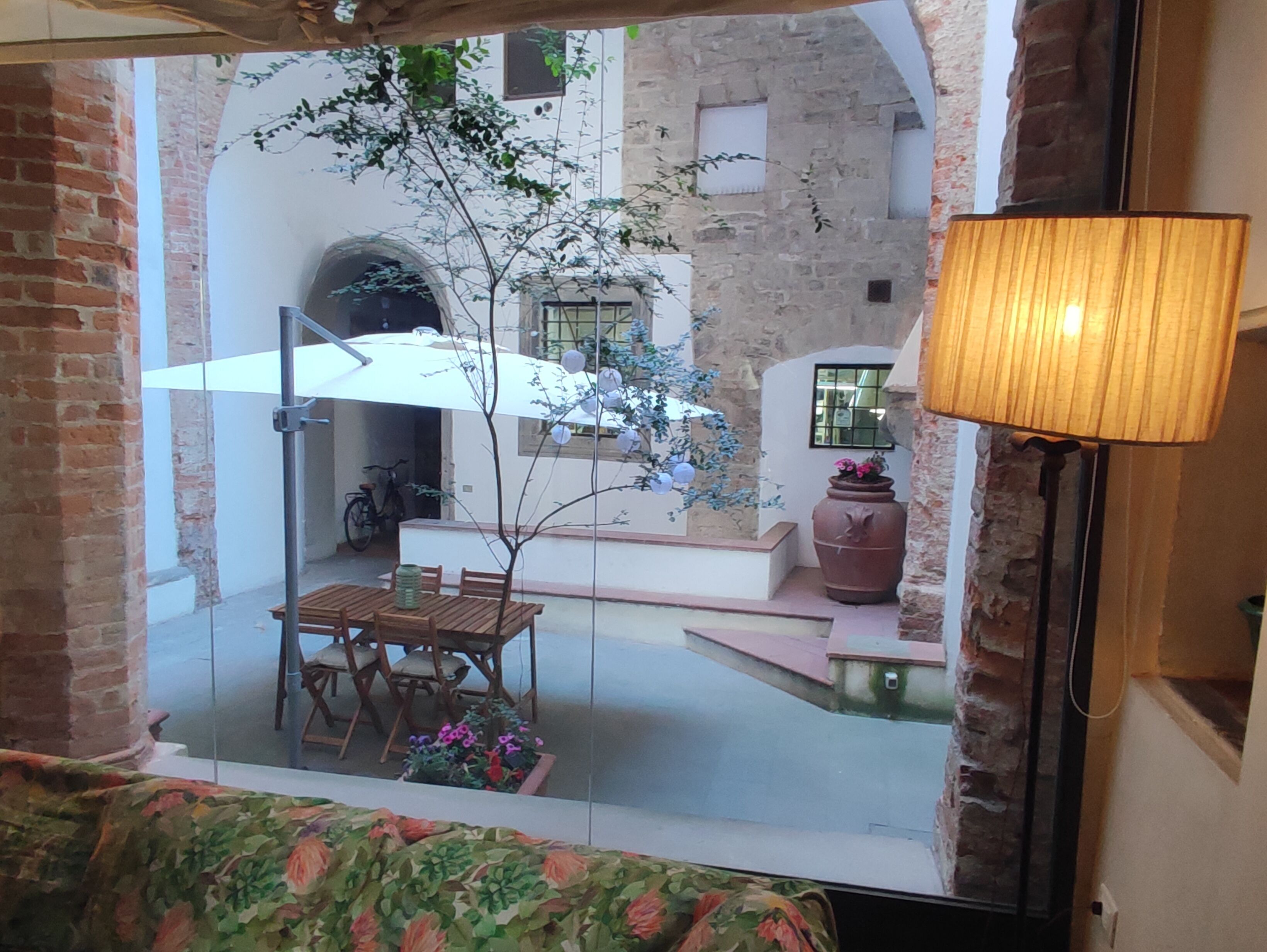A courtyard with a table and chairs, a lamp, and a potted plant.