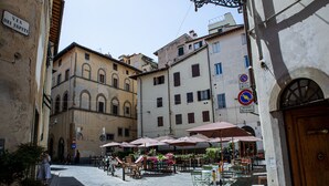 A narrow street with buildings on either side, outdoor seating with umbrellas, and a sign indicating a no parking zone. - Torre dei Sapiti Apartment with private courtyard (Firenze)