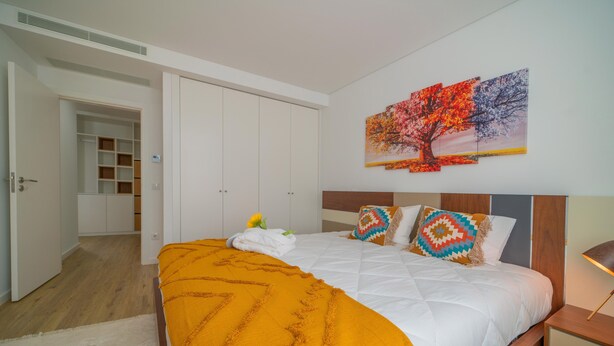 A bedroom with a bed, a wardrobe, and a painting on the wall. - NEW! 75 m2 apartment completely renovated (B) (Guimarães)