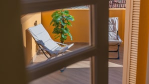 A balcony with two white lounge chairs, a potted plant, and a tiled roof. - NEW! 75 m2 apartment completely renovated (B) (Guimarães)