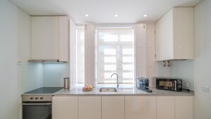 A modern kitchen with white cabinets, a built-in oven, a microwave, and a sink. - NEW! 75 m2 apartment completely renovated (B) (Guimarães)