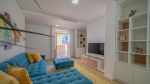 A modern living room with a blue sofa, ottoman, and white shelving unit. - NEW! 75 m2 apartment completely renovated (B) (Guimarães)
