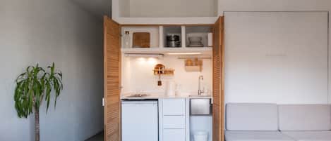 A compact kitchen with white appliances, a wooden cabinet, and a dining area with a table and chairs.