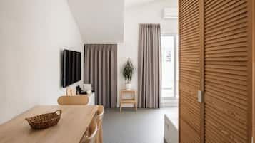 A modern room with a wooden dining table, a TV mounted on the wall, a potted plant, and a sliding wooden door.