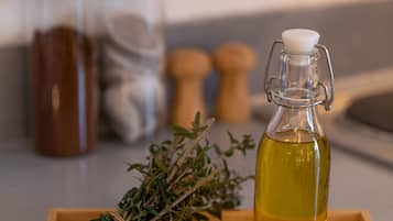 A wooden tray with a glass bottle of oil, two wooden spoons, and a bundle of herbs.