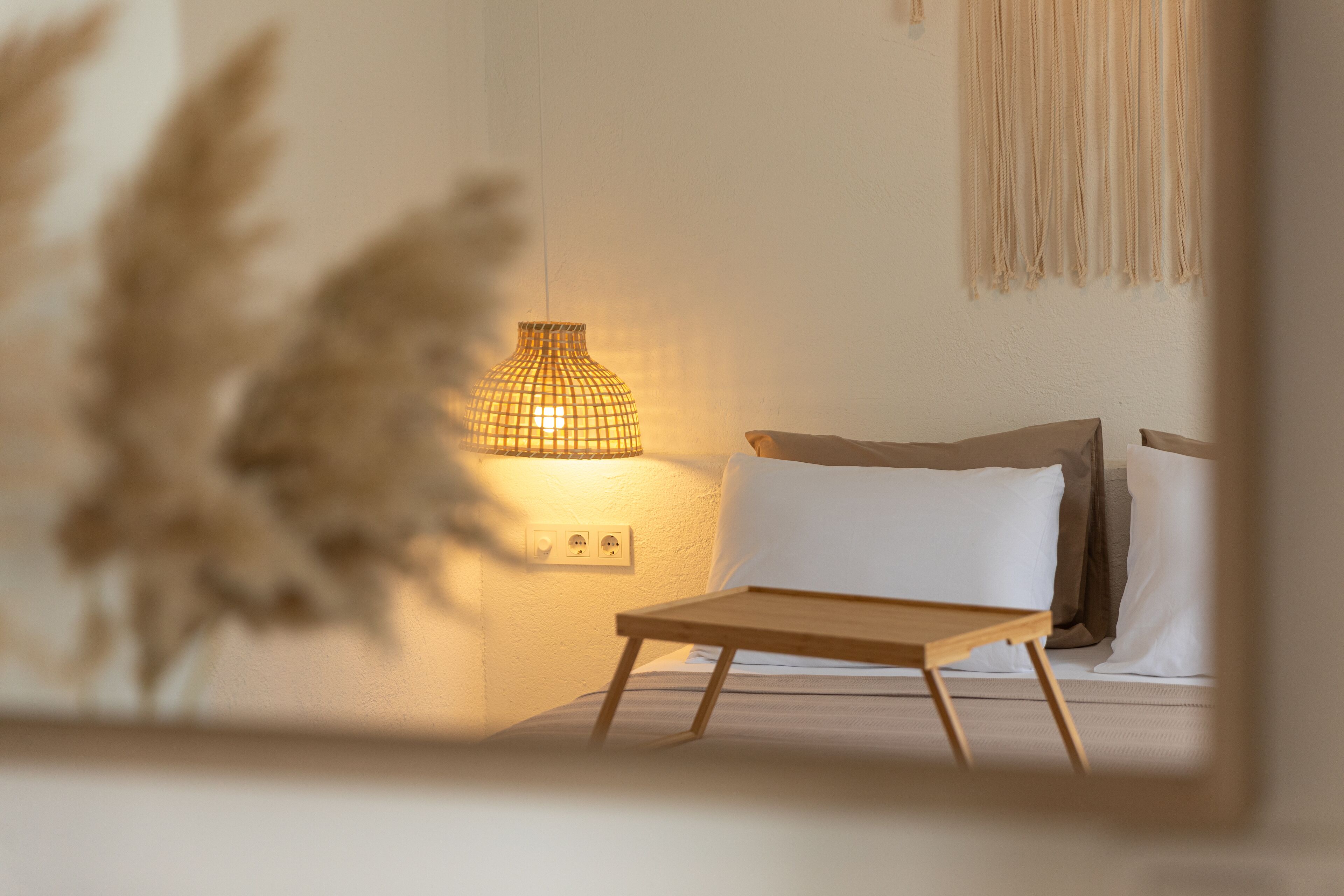 A bedroom with a bed, bedside table, lamp, and wall decor.