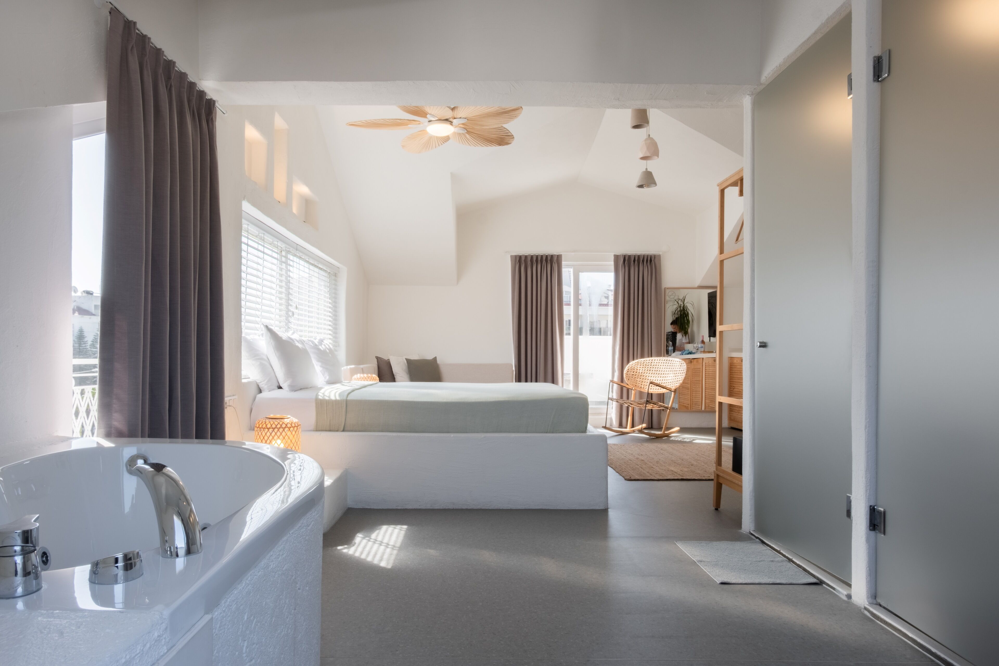Een moderne slaapkamer met een groot bad, een bed en een plafondventilator.