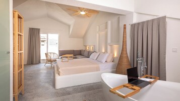 Un dormitorio moderno con una cama grande, una silla de madera, un escritorio y un baño con bañera y ducha.
