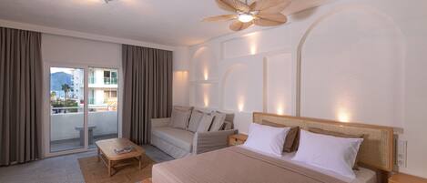 Habitación de hotel con cama, sofá, mesa de centro y ventilador de techo.