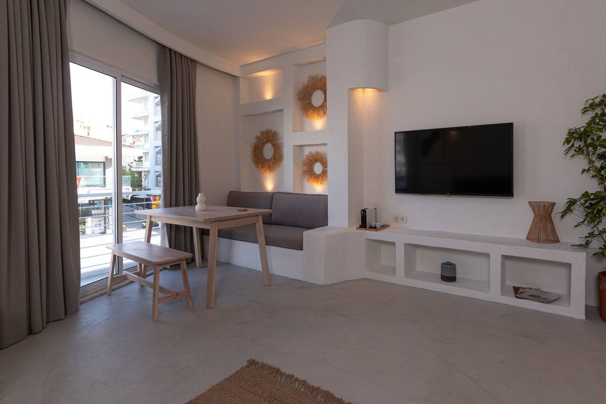 Un salon moderne avec un téléviseur à écran plat, un canapé, une table à manger et une plante en pot.