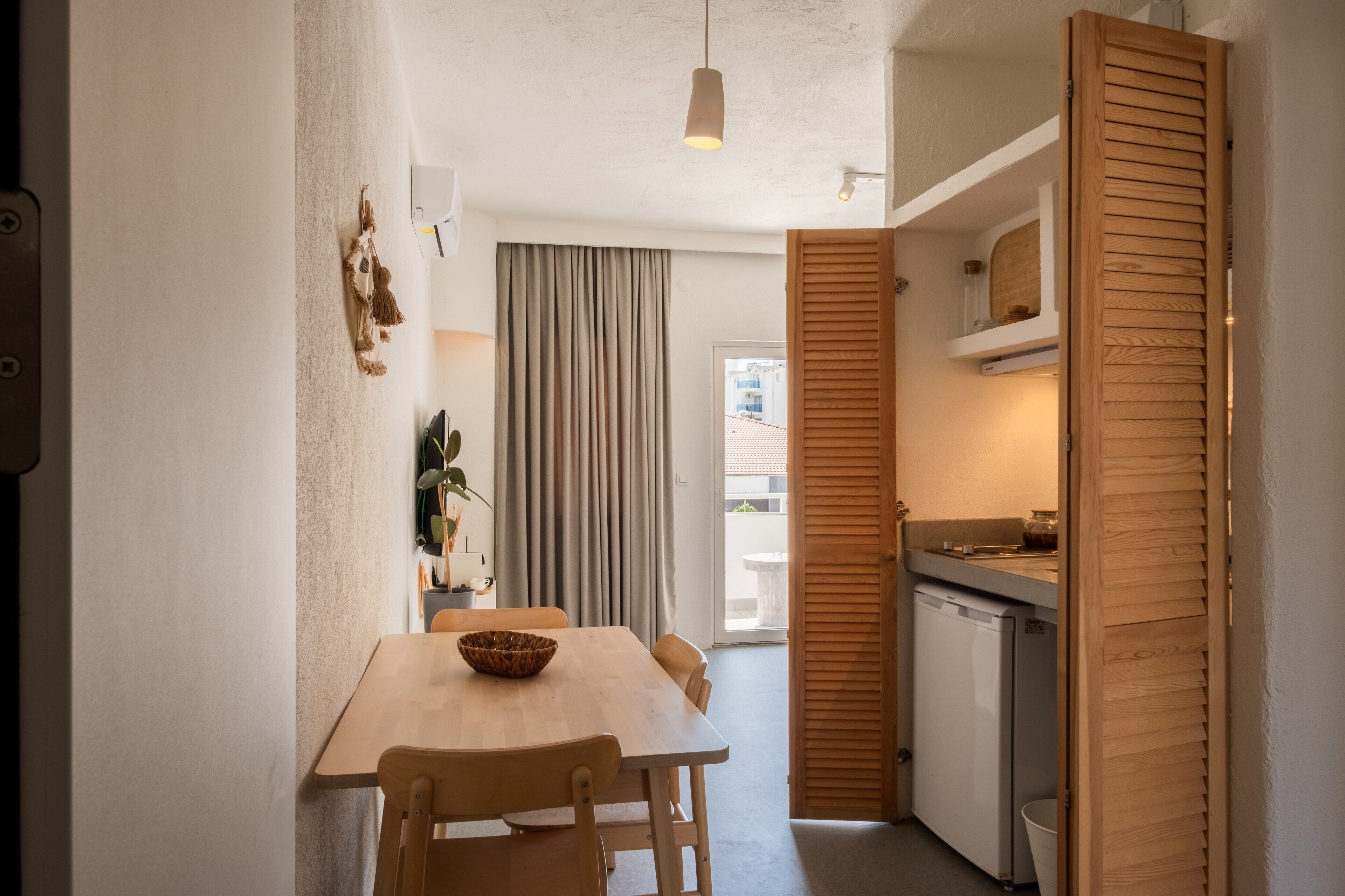 A compact kitchen with a wooden table, a refrigerator, and a sliding door.