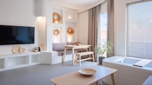 Una sala moderna con televisor de pantalla plana, un sofá, una mesa de comedor y una bañera.