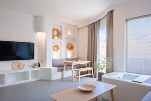 A modern living room with a flat-screen TV, a sofa, a dining table, and a bathtub.