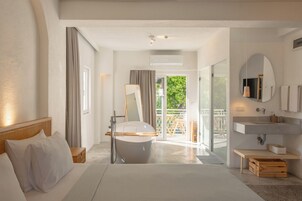 Una habitación de hotel moderna con una cama grande, una bañera, un balcón con vistas y un ba ño con lavabo y espejo.