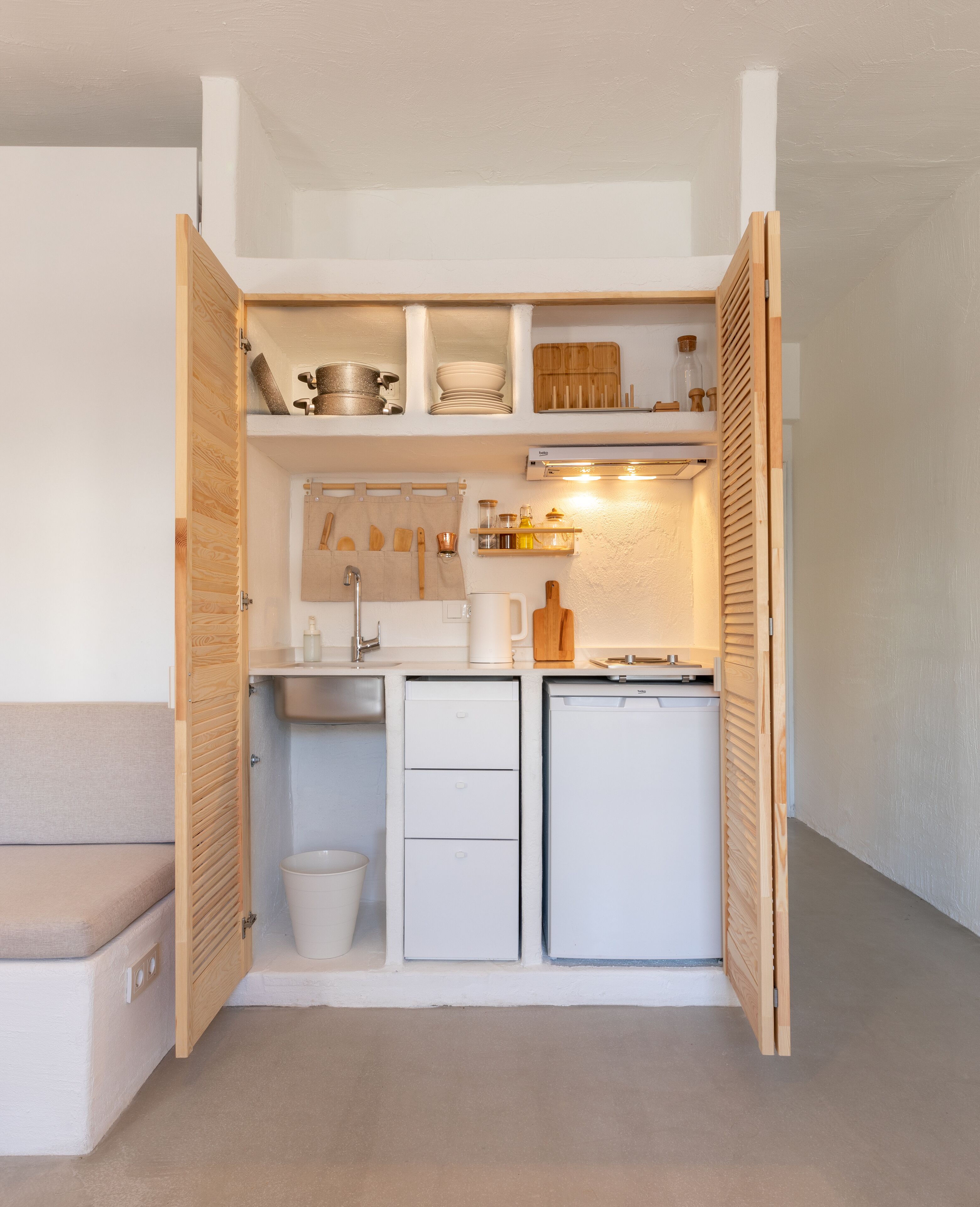 A compact kitchenette with a sink, a small refrigerator, and a countertop with various kitchen items.