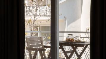 Un balcón con una silla de madera y una mesa con una jarrón de vidrio y un plato.