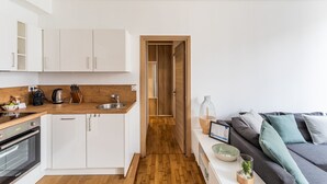 A modern kitchen with white cabinets, a wooden countertop, and a built-in oven. A wooden door leads to a hallway. - Le Cerf Volant - une pépite à l'Intramuros (Saint-Malo)
