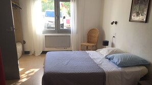 A bedroom with a bed, a chair, a lamp, and a radiator. - Appartement Rez de Jardin Piscine Chauffée, Barbecue, Plancha (Argelès-sur-Mer)
