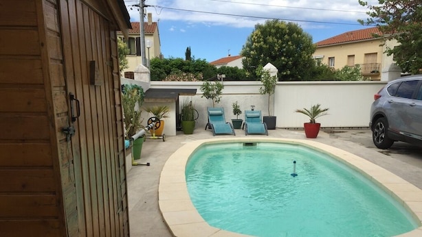 A swimming pool with a tiled deck, lounge chairs, and potted plants. - Appartement Rez de Jardin Piscine Chauffée, Barbecue, Plancha (Argelès-sur-Mer)
