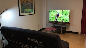 A living room with a couch, a television, and a framed picture on the wall. - Appartement Rez de Jardin Piscine Chauffée, Barbecue, Plancha (Argelès-sur-Mer)