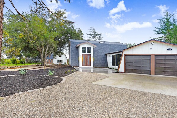 A modern two-story house with a garage, a well-maintained garden, and a clear sky.