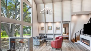 A spacious living area with a large window, a fireplace, and a modern chandelier. - Chardonnay Estate - 6 Suites in the heart of wine region 2 ml from Sonoma Square (Sonoma)