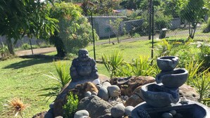 En trädgård med en stenformation, en Buddha-staty och ett vattenelement.