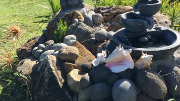 Ein Garten mit Steinanlage, Buddha-Statue und Wasserspiel.