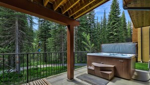 Ein Balkon mit Whirlpool, Holzterrasse und Blick auf ein bewaldetes Gebiet.