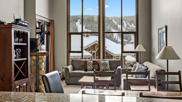 A cozy living room with a large window overlooking a snowy mountain landscape. - Pet Friendly, Ski In/Ski Out, 3 Bedroom Condo in Stone's Throw! (Sun Peaks)